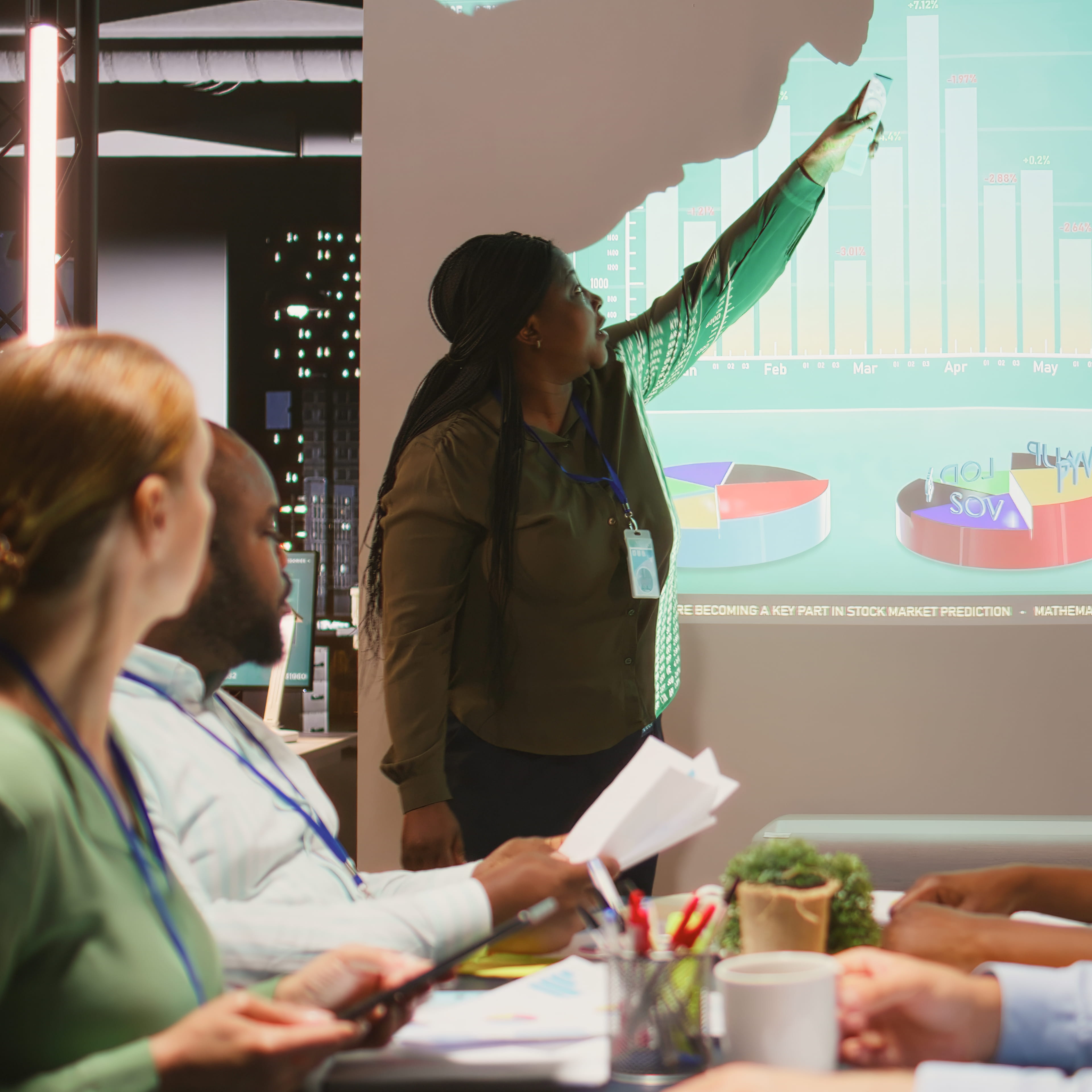 Presenter pointing at data charts during a meeting, representing narrative architecture development