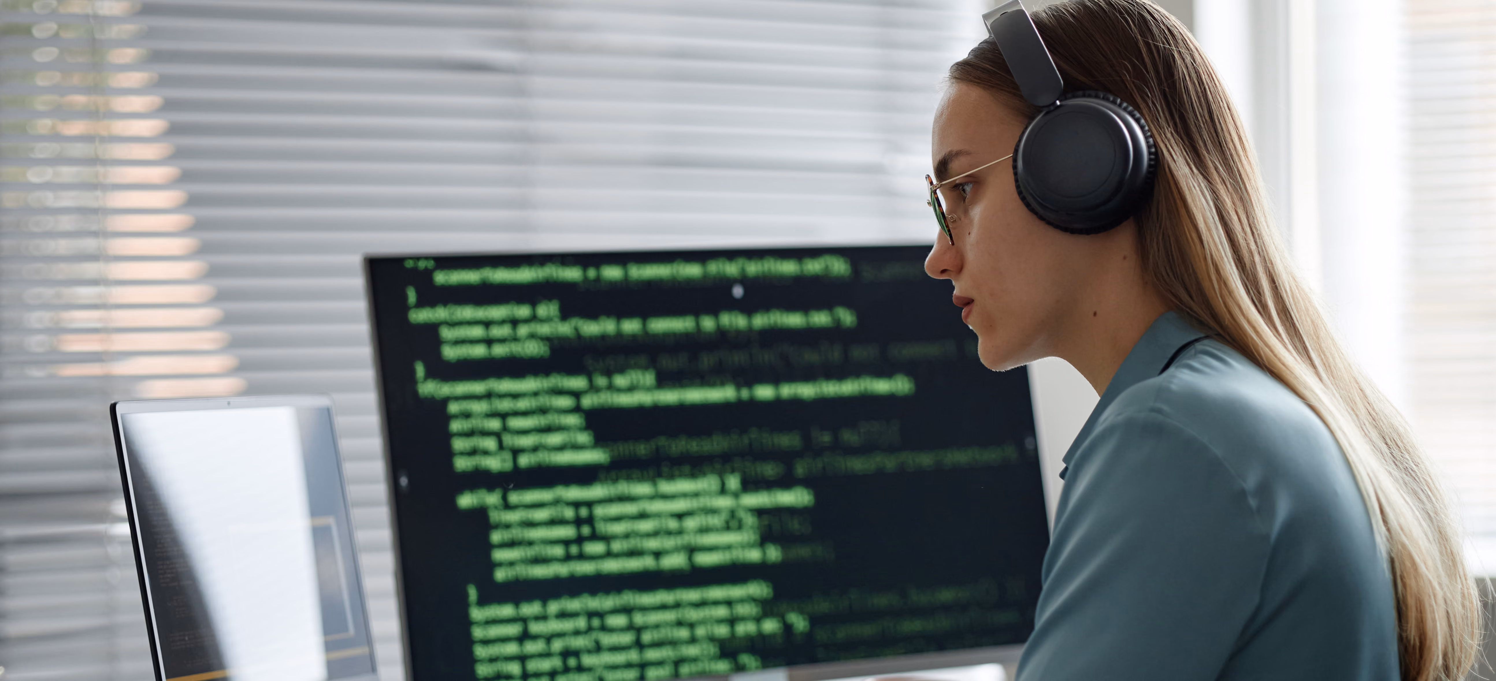 Developer wearing headphones while viewing code on a monitor, representing technology and SaaS
