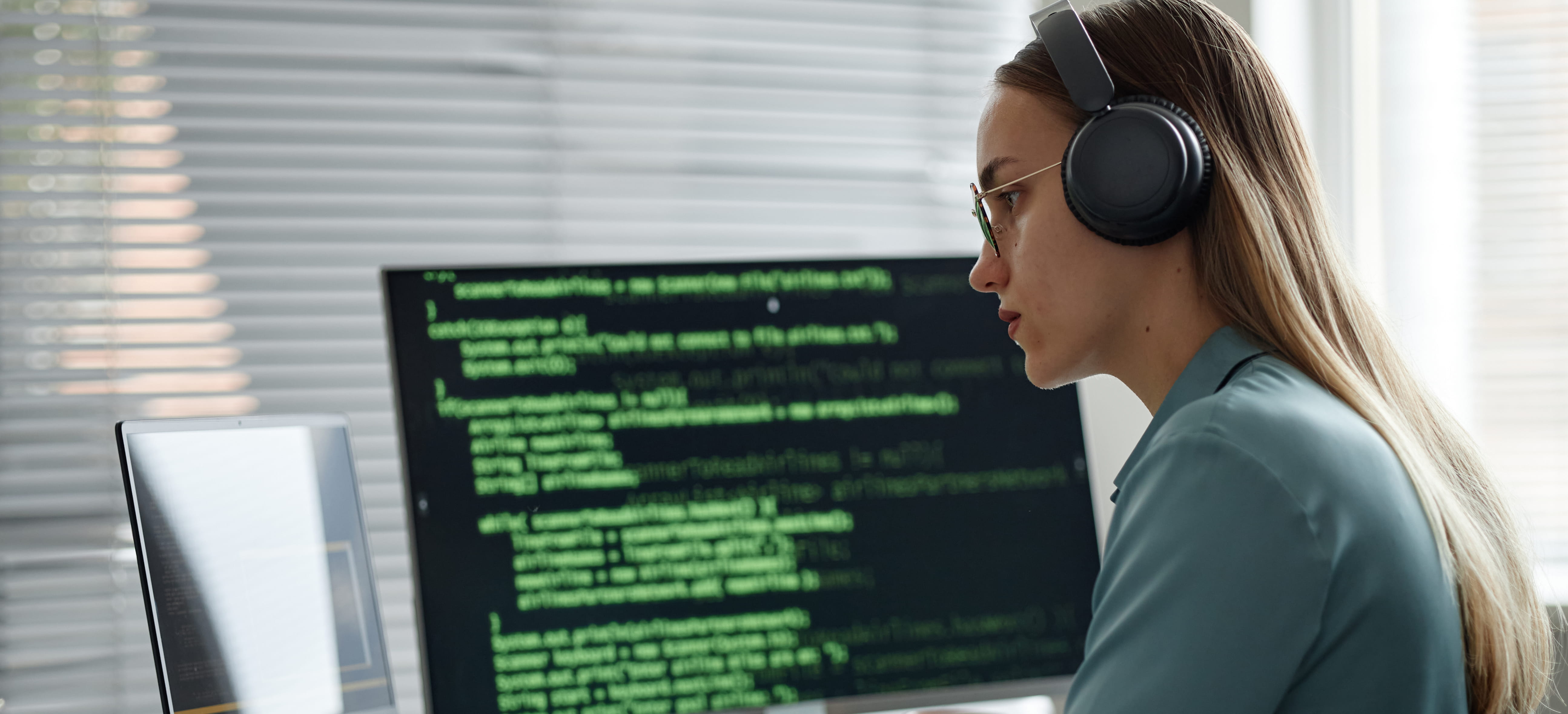 Software professional coding on a computer while wearing headphones in a modern SaaS technology workspace.