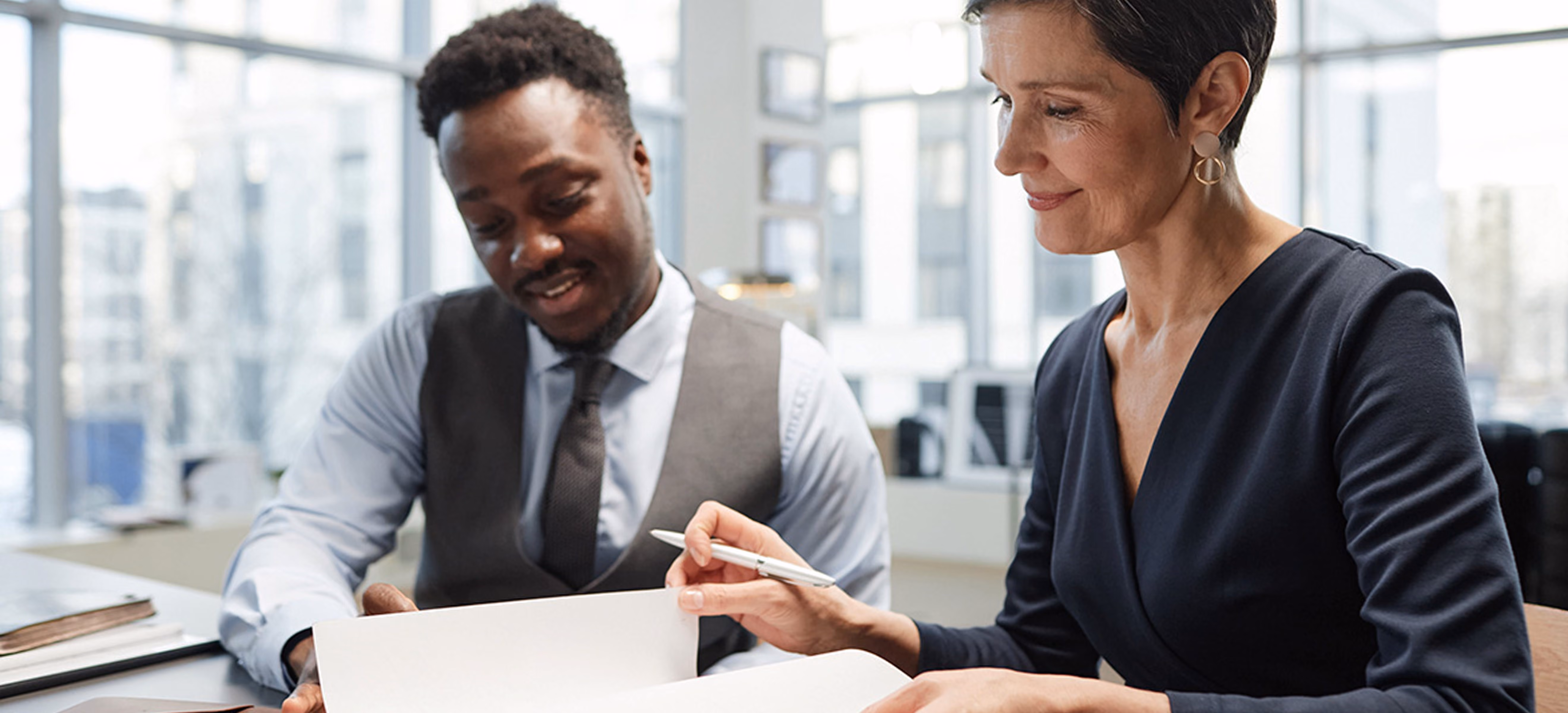 Two professionals reviewing a document together in an office, representing professional services