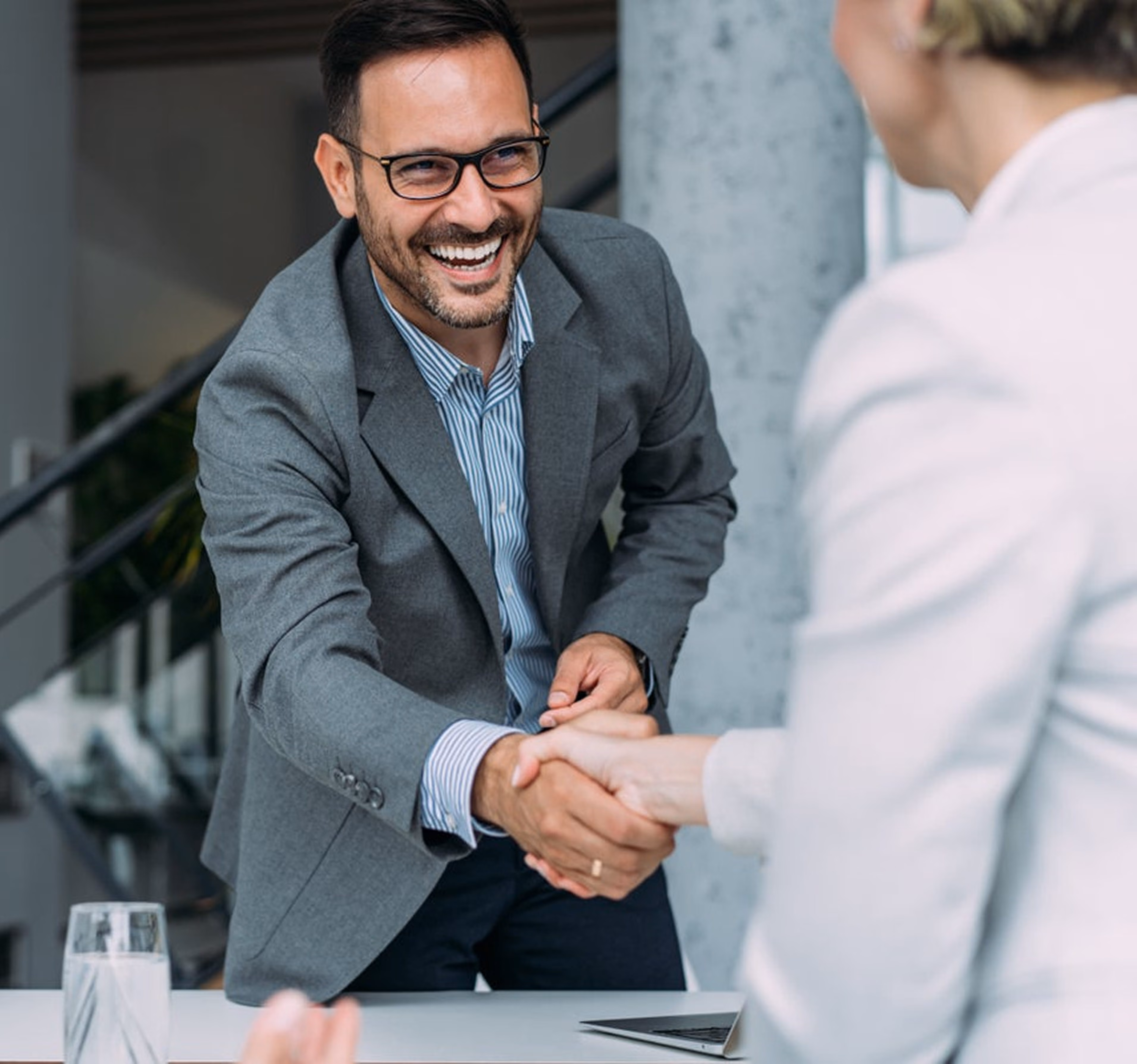 Business consultant shaking hands with a client after a successful management consulting meeting and agreement.