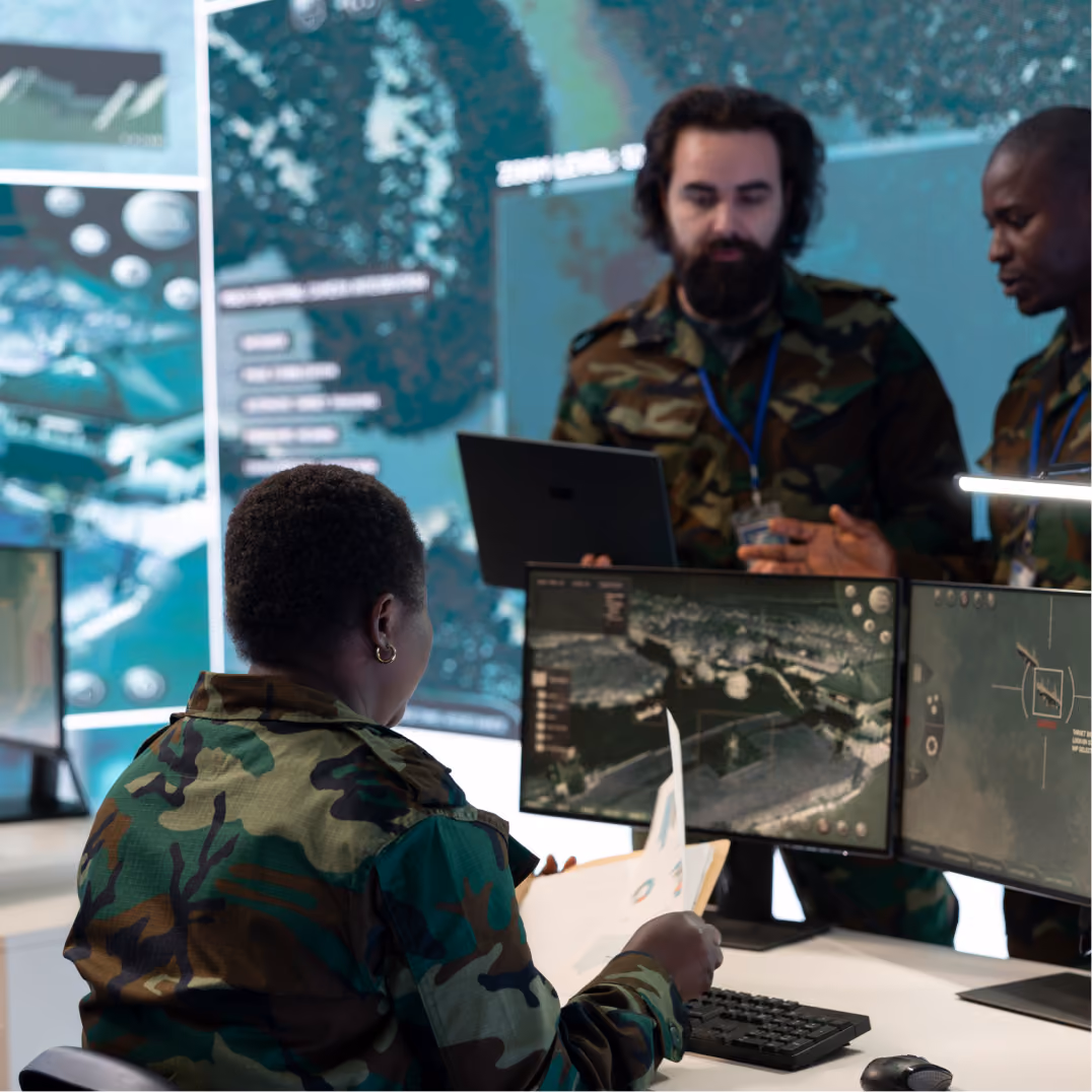  Defense professionals reviewing intelligence data on monitors in a secure operations center supporting mission