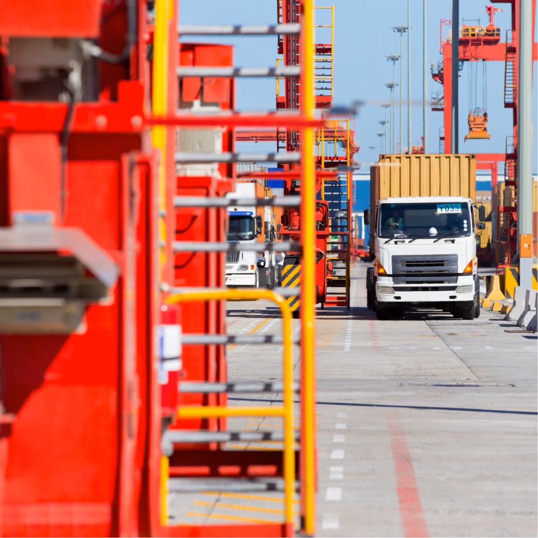 Cargo truck moves through a busy shipping terminal with cranes supporting efficient logistics operations daily