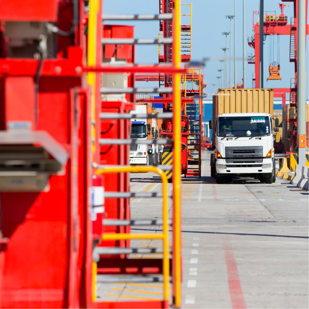 Cargo truck moves through a busy shipping terminal with cranes supporting efficient logistics operations daily