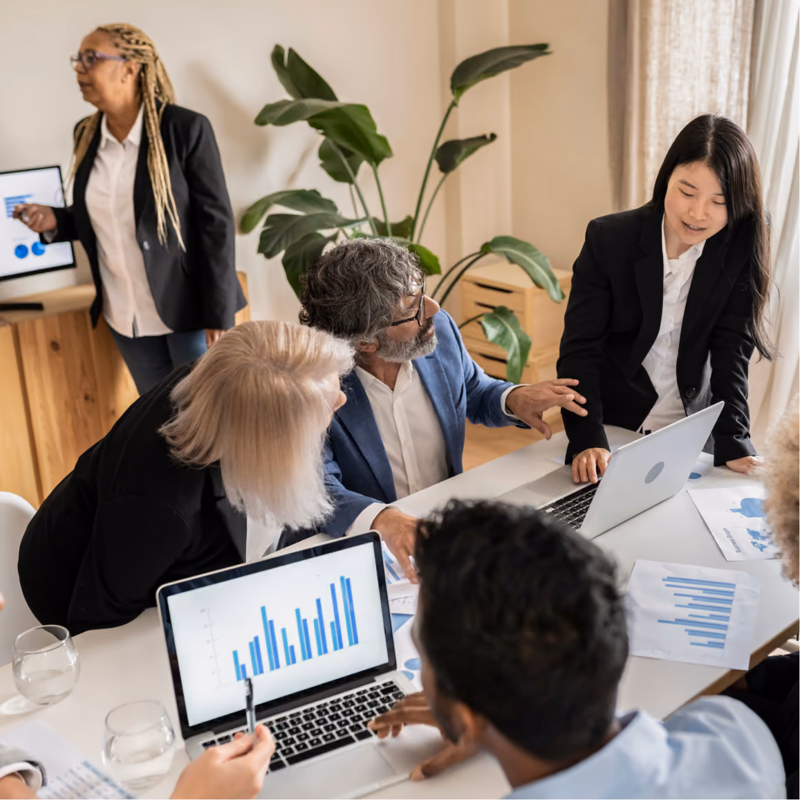 Business team analyzes reports and charts while planning strategy together in a collaborative meeting room.