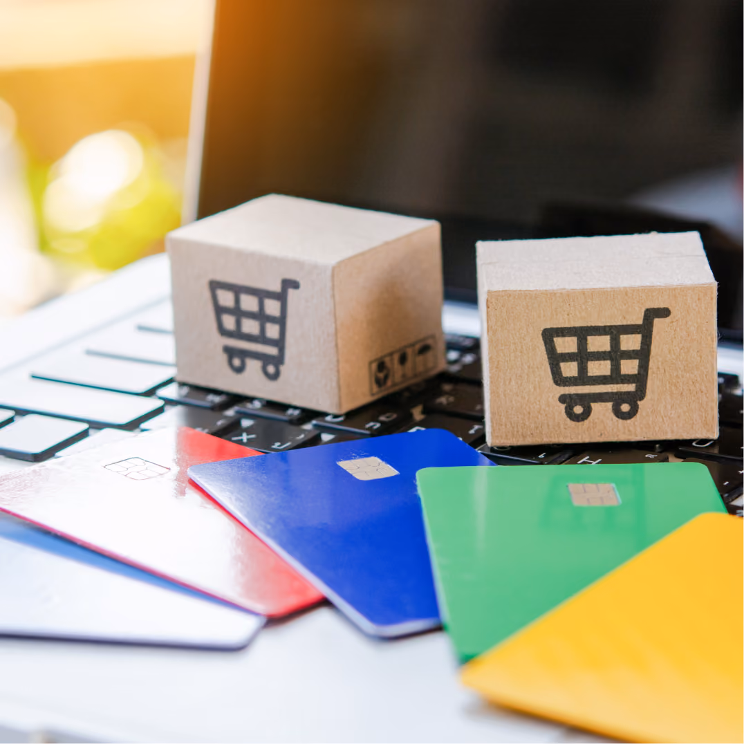  Miniature cardboard shopping boxes and colorful credit cards resting on a laptop keyboard for online shopping.