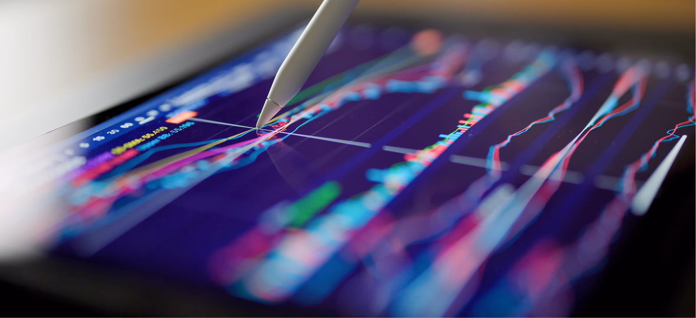 : Close-up of a stylus pointing at a colorful stock market chart displayed on a tablet screen, tracking prices.
