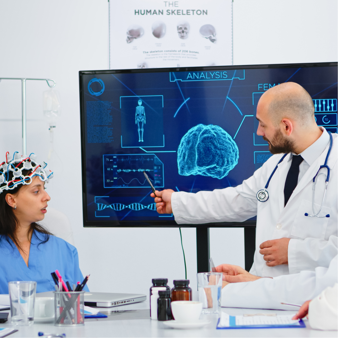 Academic Medical Centers and Hospital Systems Doctor explaining brain scan to medical team during neuroscience meeting using digital display and EEG analysi