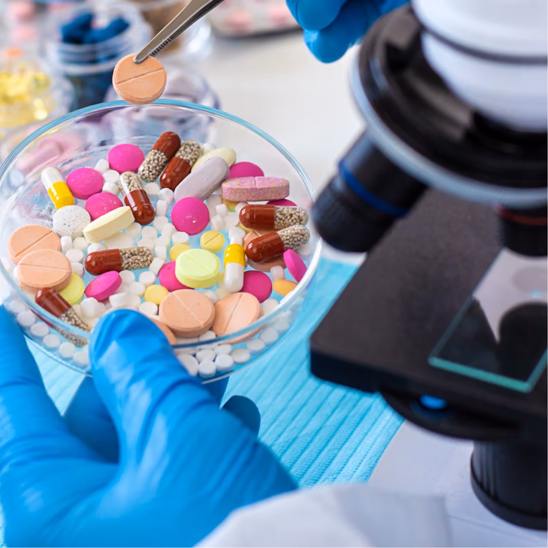 Researcher inspects assorted pharmaceutical tablets in laboratory for quality testing using microscope and pre