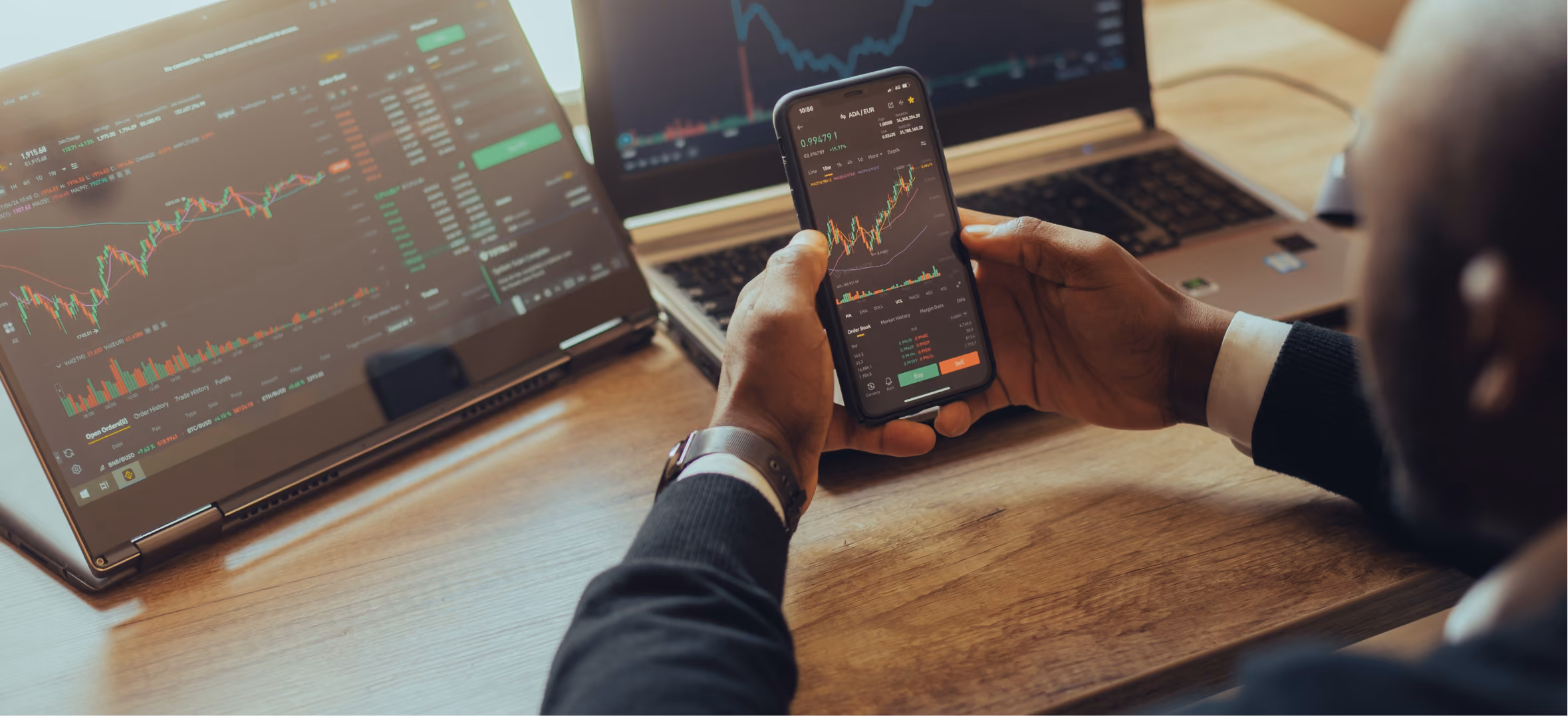 Investor reviews live trading charts on smartphone and laptops for fintech portfolio management and market ana
