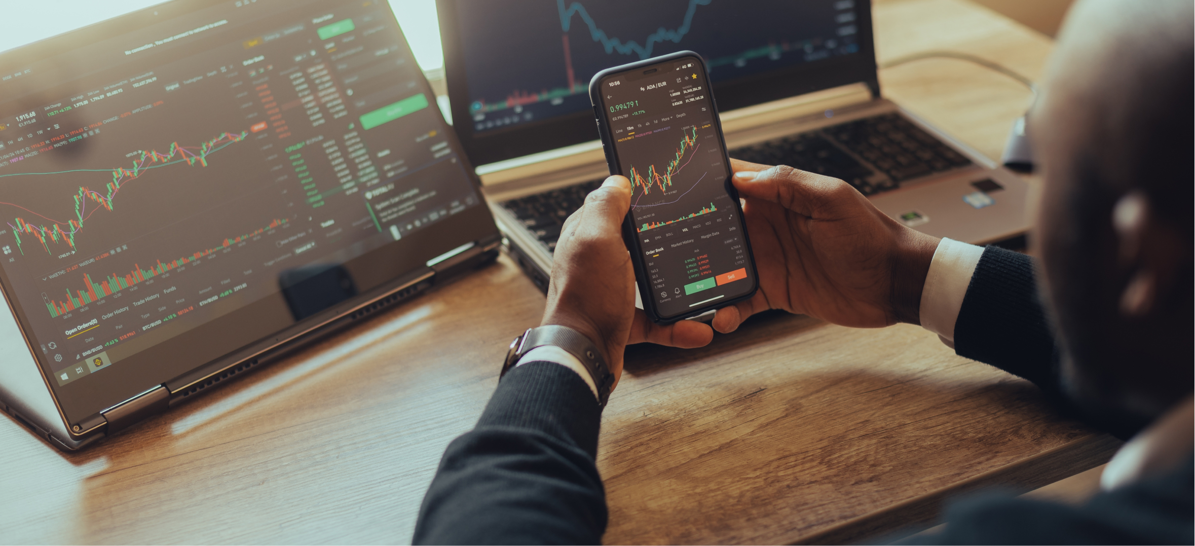 Investor reviews live trading charts on smartphone and laptops for fintech portfolio management and market ana
