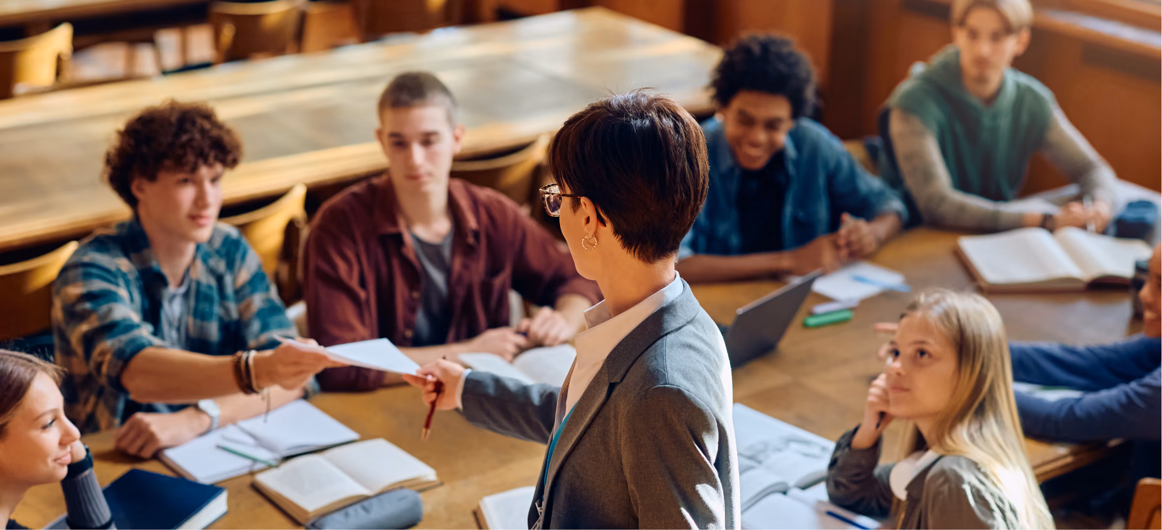 University instructor hands paper to student during collaborative classroom discussion with engaged learners a