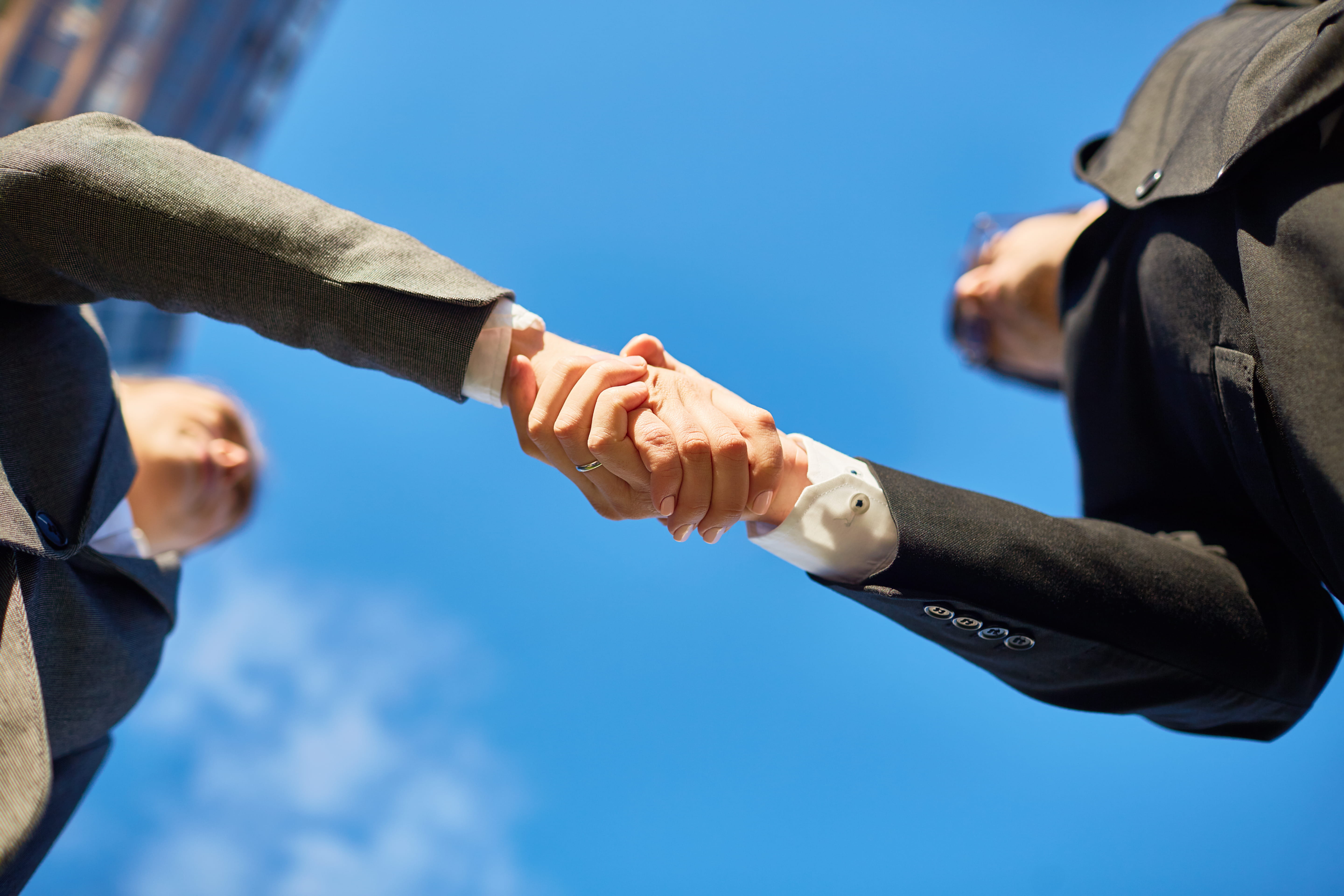 Professionals shaking hands outside representing investor relations, partnerships, and stakeholder confidence.