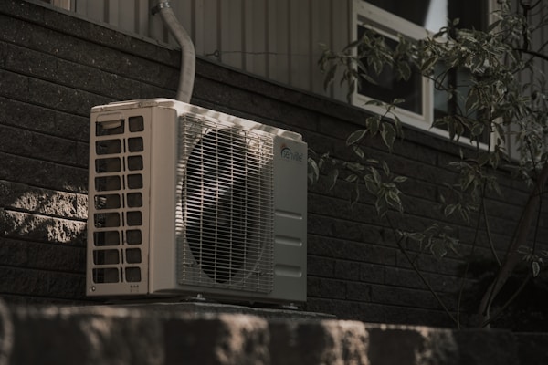 a white air conditioner sitting on top of a brick wall