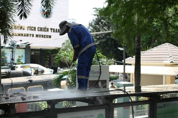 Worker pressure washing a surface outdoors