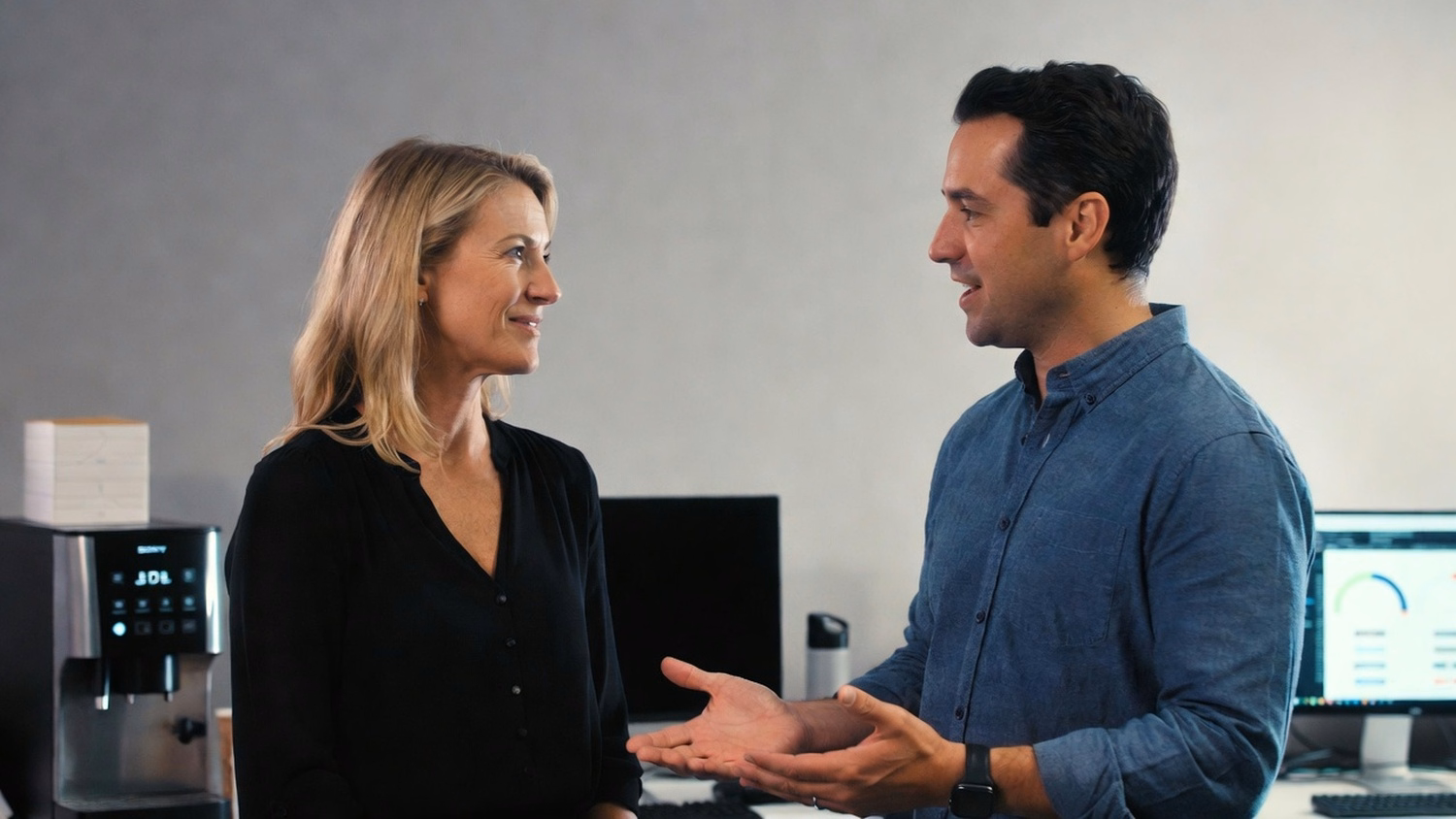 Colleagues discuss business strategy by coffee machine