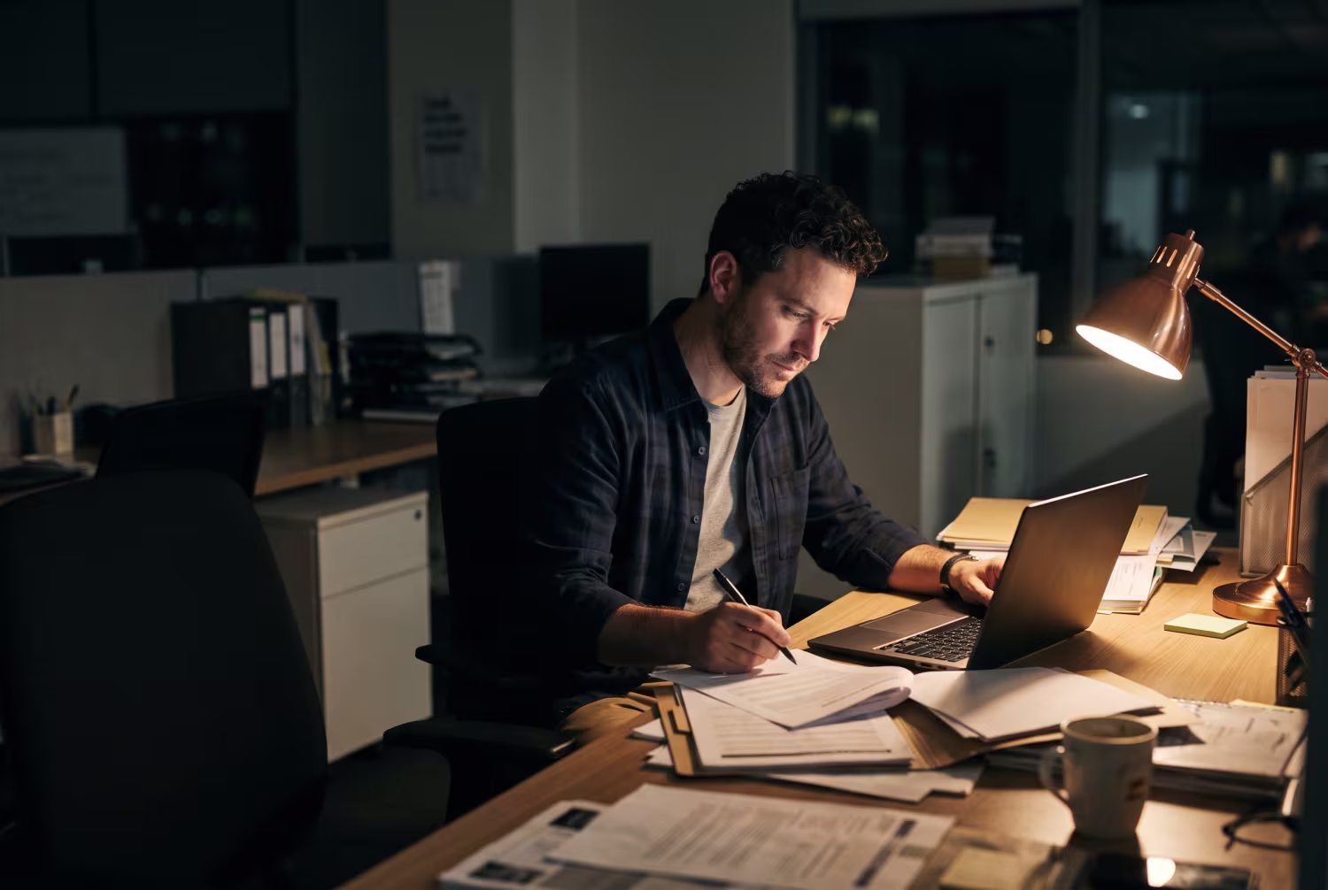 IT manager at desk reviewing compliance policies after hours