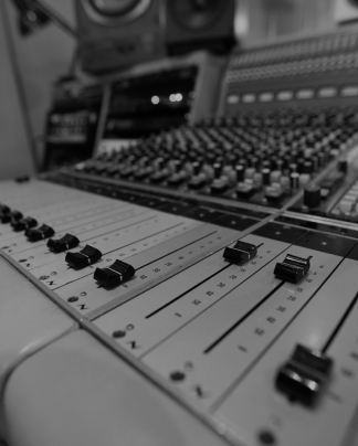 Close-up of audio mixing console sliders and knobs in a recording studio.
