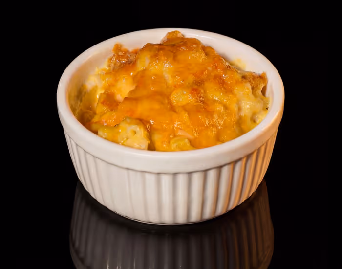 Baked mac and cheese with a golden melted cheese crust served in a white ramekin.