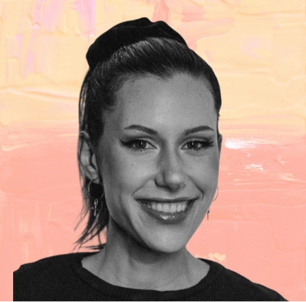 Smiling young woman with pulled-back hair wearing a black top and small hoop earrings.