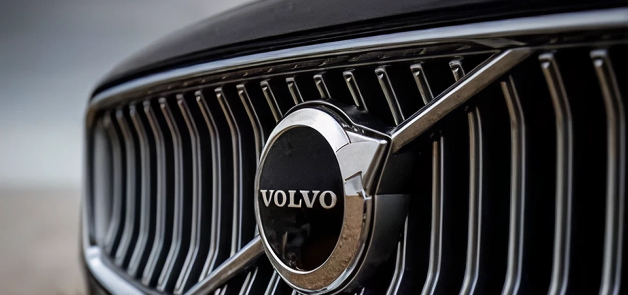Close-up of a Volvo car front grille featuring the Volvo emblem with a diagonal bar across vertical slats.