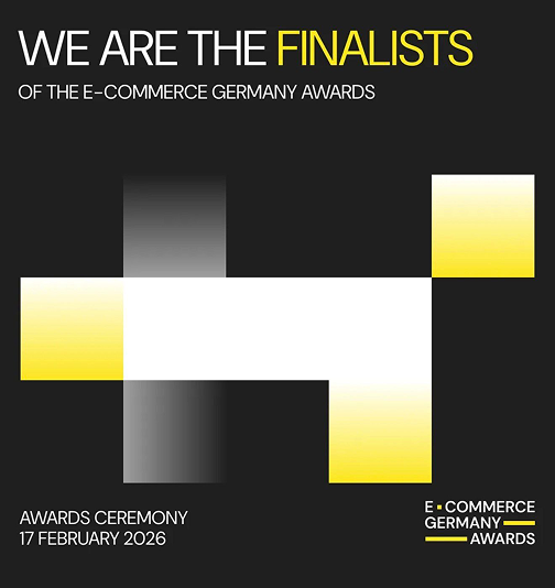 Text saying 'WE ARE THE FINALISTS OF THE E-COMMERCE GERMANY AWARDS' with award ceremony date 17 February 2026, accompanied by a cross-shaped gradient graphic in black, white, gray, and yellow, and the E-Commerce Germany Awards logo on a black background.