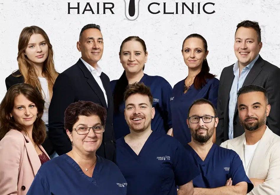 Group portrait of a diverse team of ten smiling medical and office professionals, some wearing blue scrubs, posing in front of a white background with partial 'HAIR CLINIC' text visible above them.