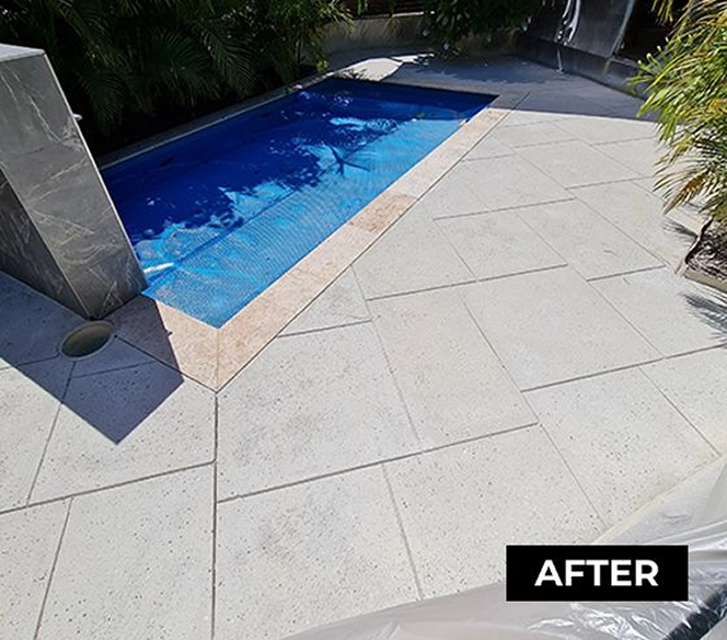 Clean and renovated outdoor swimming pool with clear blue water, surrounded by light-colored, neatly arranged concrete tiles and bordered by plants, with the word 'AFTER' indicating a completed makeover.