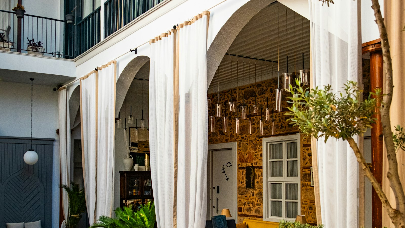 Cour intérieure d'un hôtel avec terrasse de restaurant sous des arcades blanches : avocat des hôtels, cafés, restaurants et discothèques