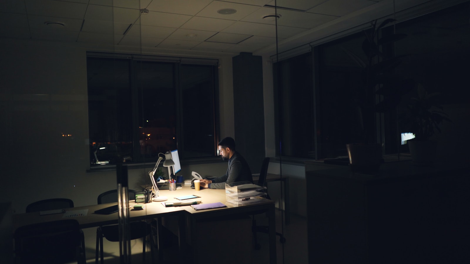 Salarié épuisé travaillant tard à son bureau, illustrant le travail pendant un arrêt maladie