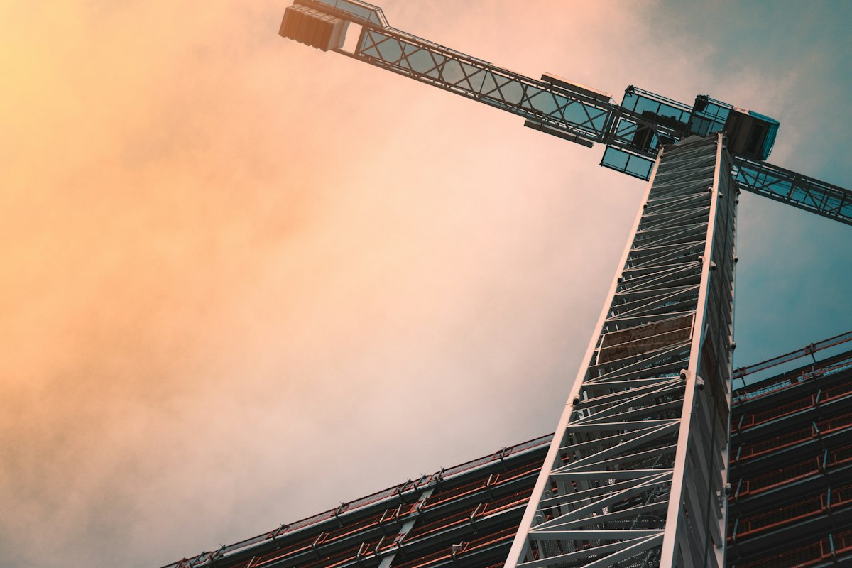 Cotisation intempéries 2026-2027 : grue de chantier du BTP sous un soleil couchant