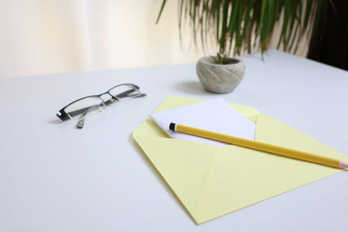 Avis de contrôle Urssaf : lunettes, crayon et note posés sur une enveloppe jaune
