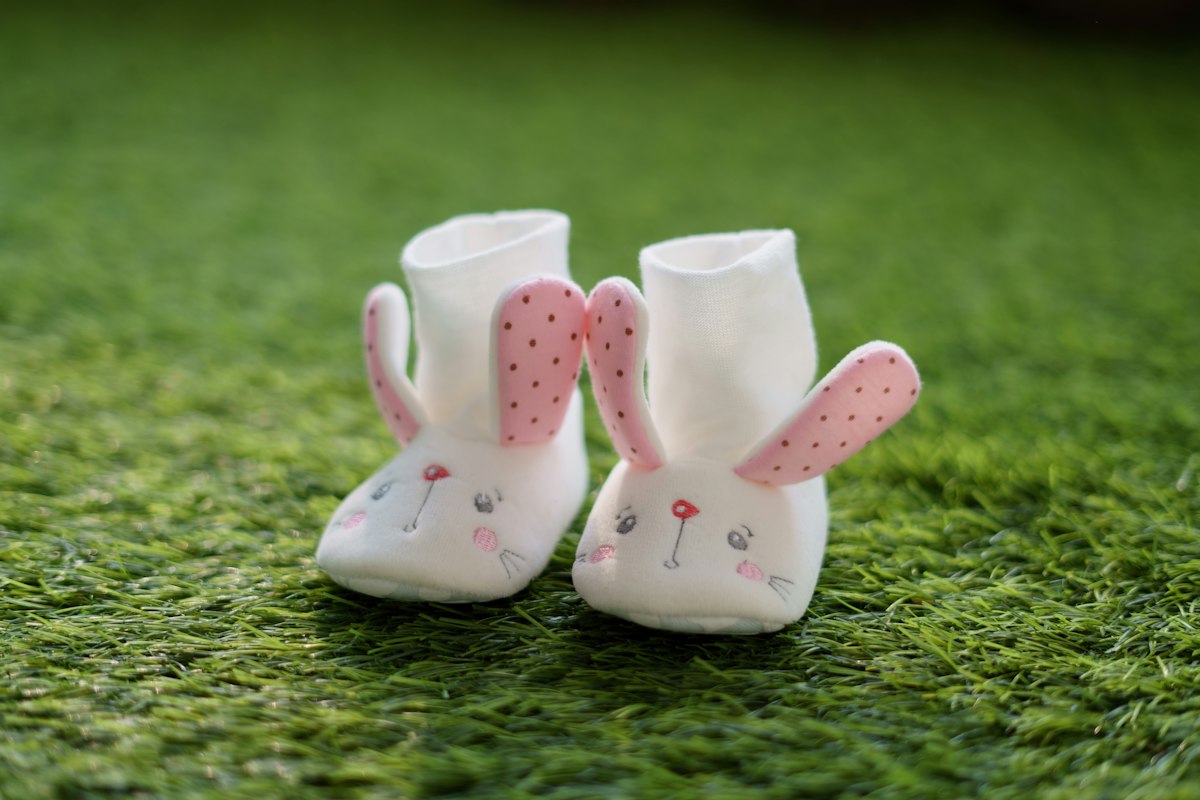 Congé de naissance, mutuelle et voiture de fonction : chaussons de bébé blancs posés sur l'herbe