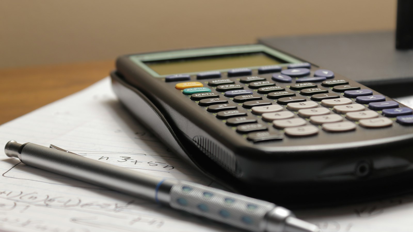 Calculatrice et stylo posés sur une feuille de calculs : contrôles et cotisations sociales des OGEC