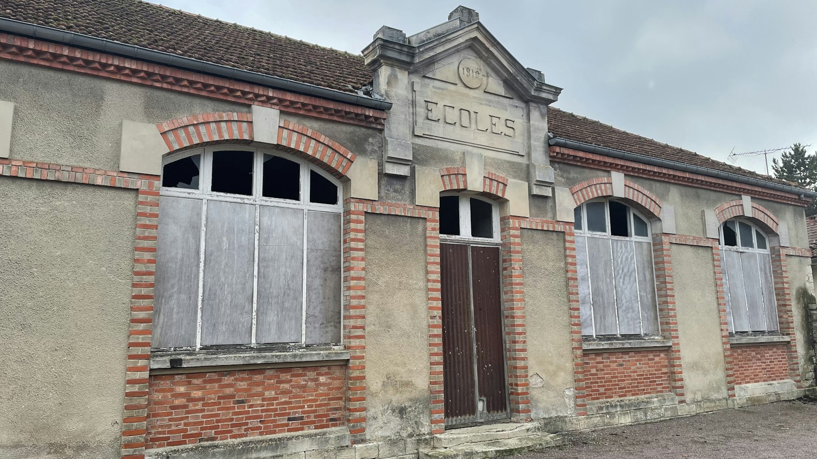 Ancien bâtiment d'école en brique et pierre, fronton gravé du mot Écoles : restructurations des OGEC