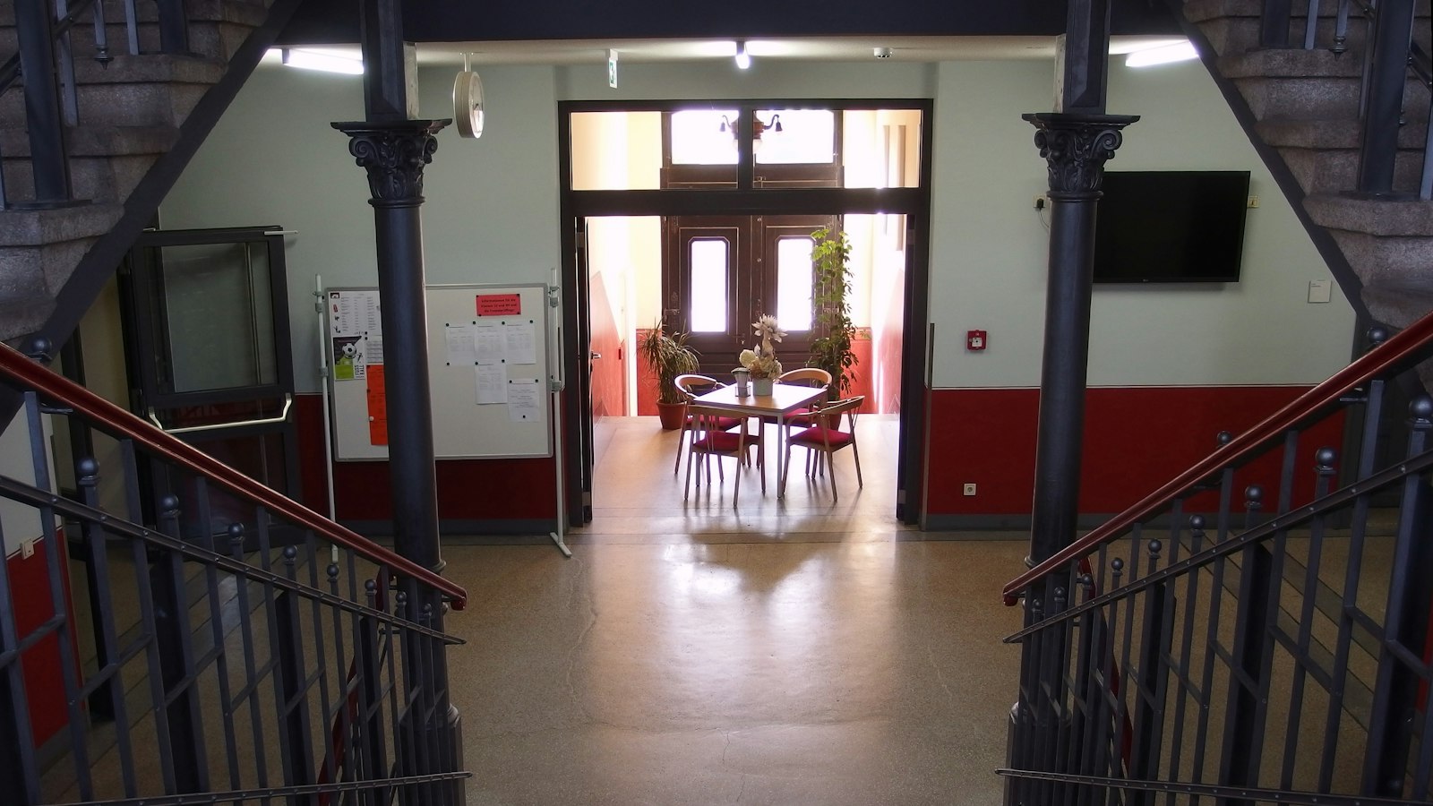 Escalier et hall d'un bâtiment scolaire ancien, colonnes en fonte : santé et sécurité dans l'établissement OGEC