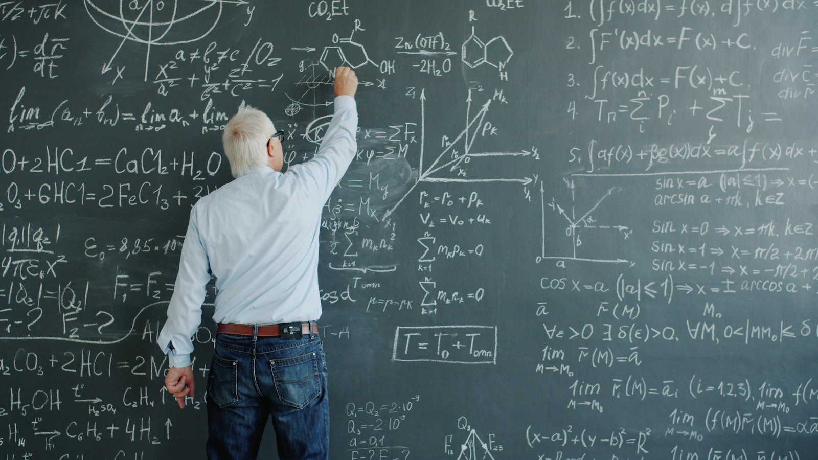 Enseignant de dos écrivant des formules à la craie sur un tableau noir : enseignants agents publics de l'État