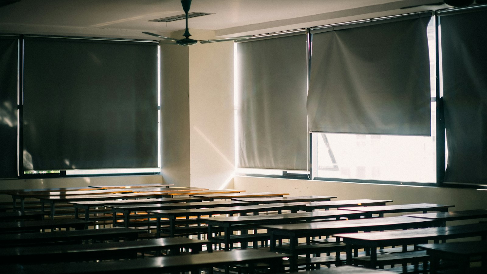 Salle de classe vide, stores baissés et rangées de tables au soleil : heures de délégation des enseignants