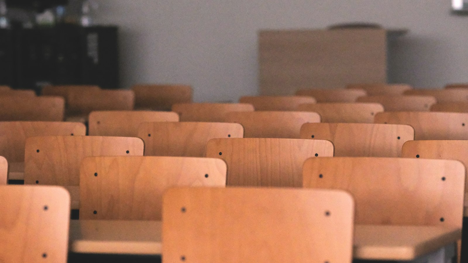 Rangées de chaises et de tables en bois dans une salle de classe : CSE et calcul de l'effectif de l'OGEC
