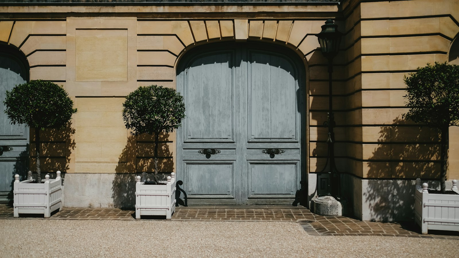 Porte cochère ancienne d'un bâtiment en pierre, cour gravillonnée : le président d'OGEC, bénévole de l'association