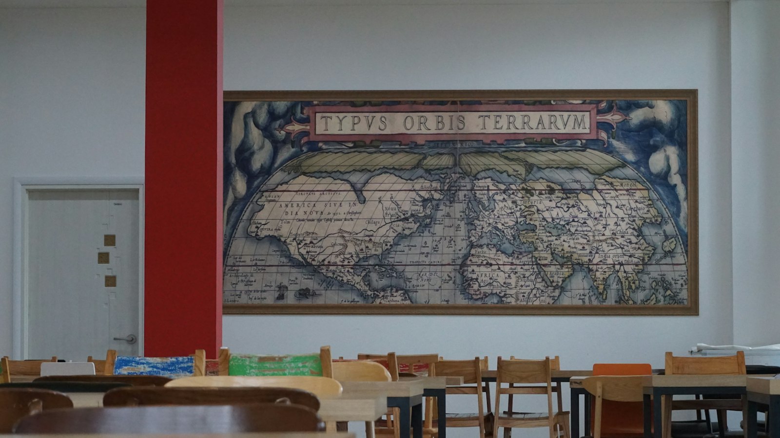 Mappemonde ancienne au mur d'une salle garnie de tables et de chaises en bois : réseau UDOGEC, UROGEC et FNOGEC
