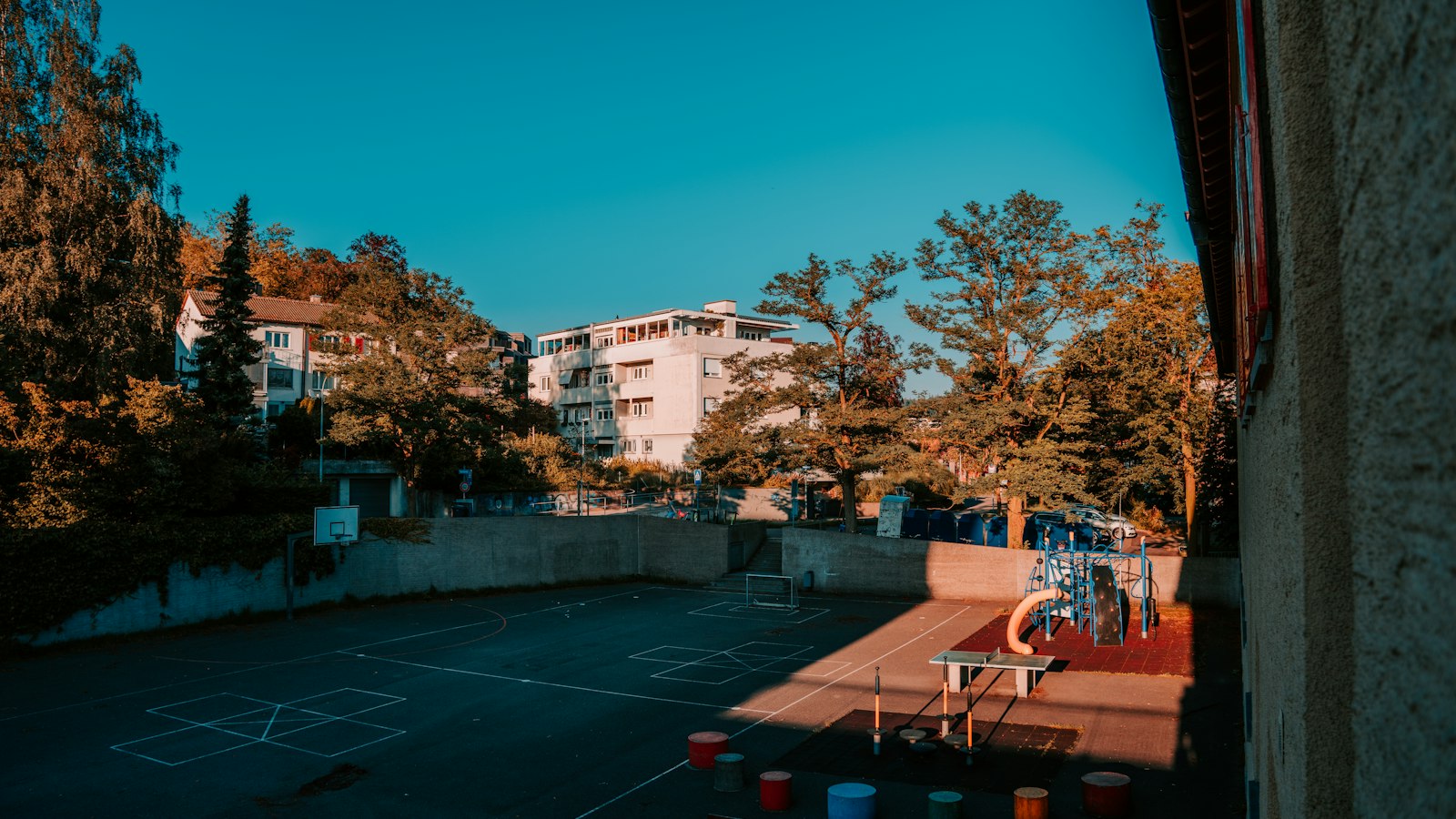 Cour d'école vide un soir d'été, jeux tracés au sol : congés payés et fermeture de l'établissement OGEC