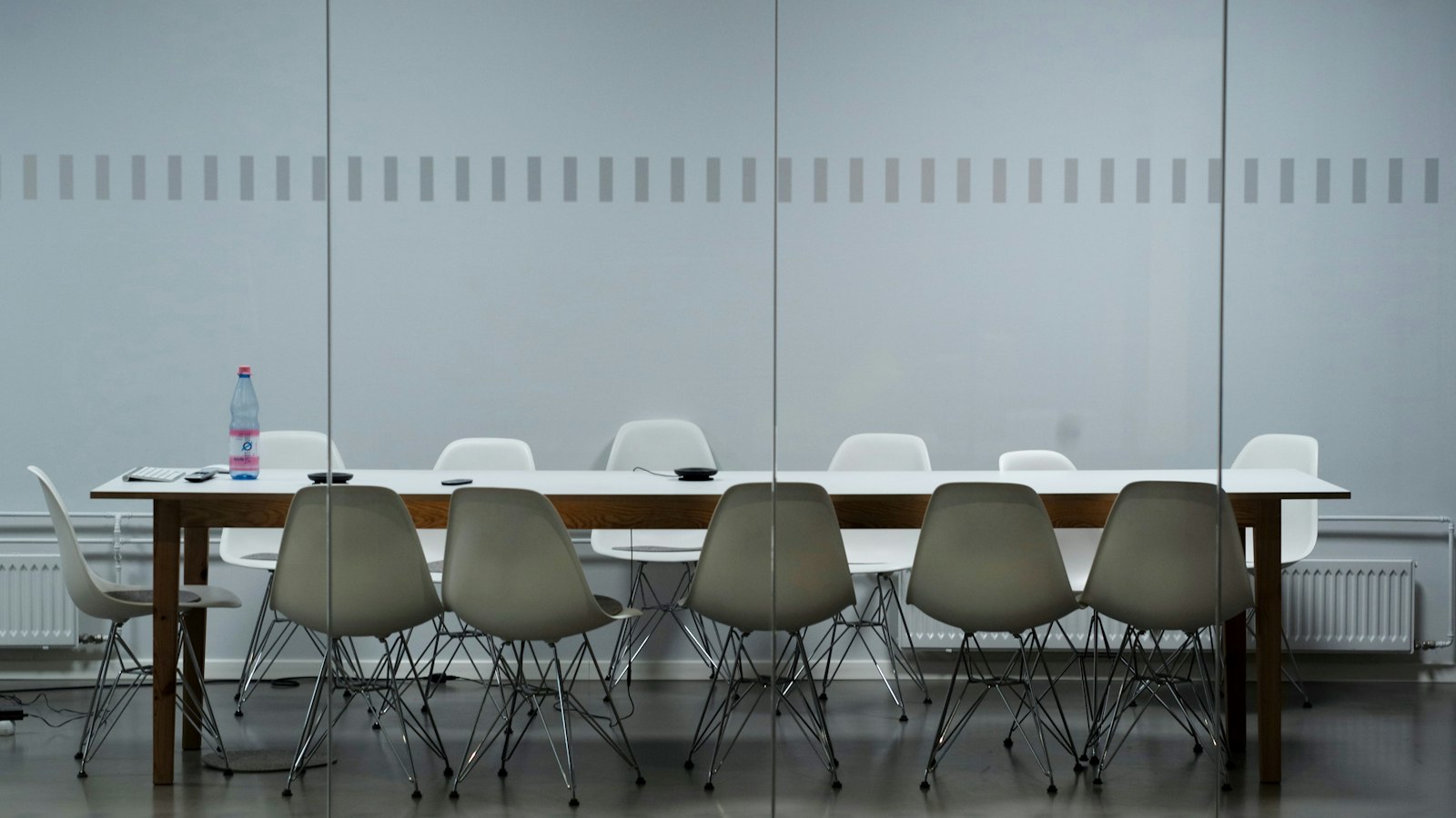 Salle de réunion sobre avec longue table et chaises grises : les consultations du CSE de l'OGEC