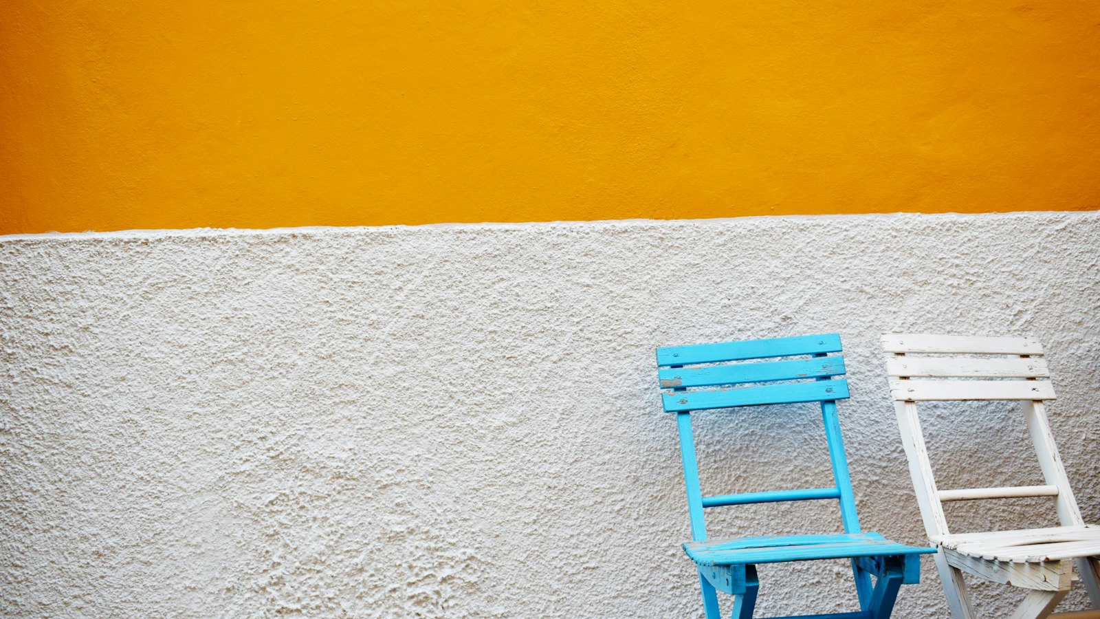 2 chaises de couleurs différentes contre un mur : les conflits entre enseignants agents publics et salariés de l'OGEC