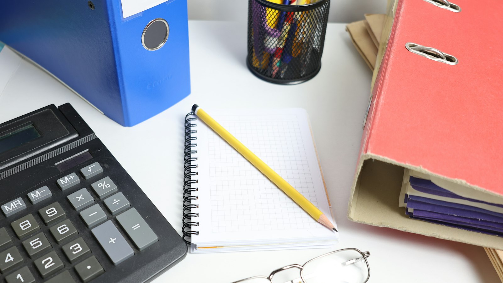 Calculatrice, classeurs et lunettes sur un bureau : contrôle Urssaf d'un OGEC