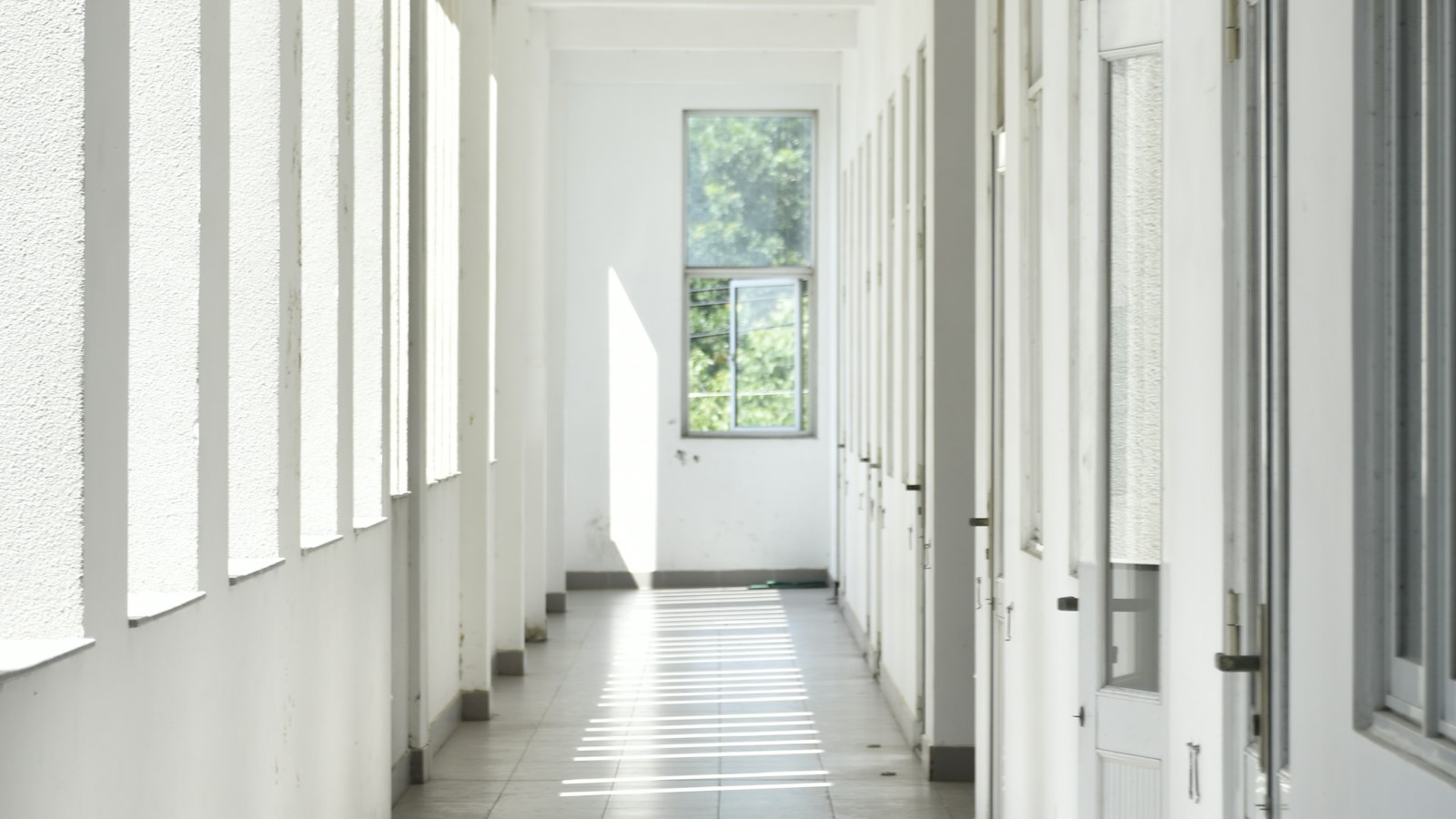 Couloir d'école ensoleillé bordé de portes : mise à disposition de personnel entre OGEC