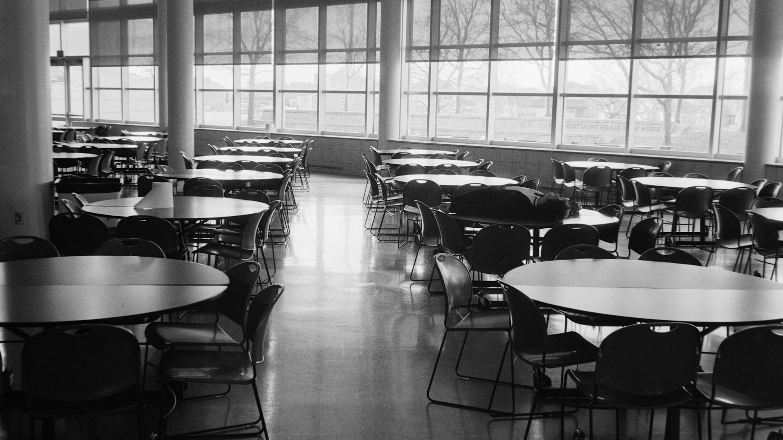 Salle de restauration scolaire vide aux tables rondes : les pauses et la surveillance des repas
