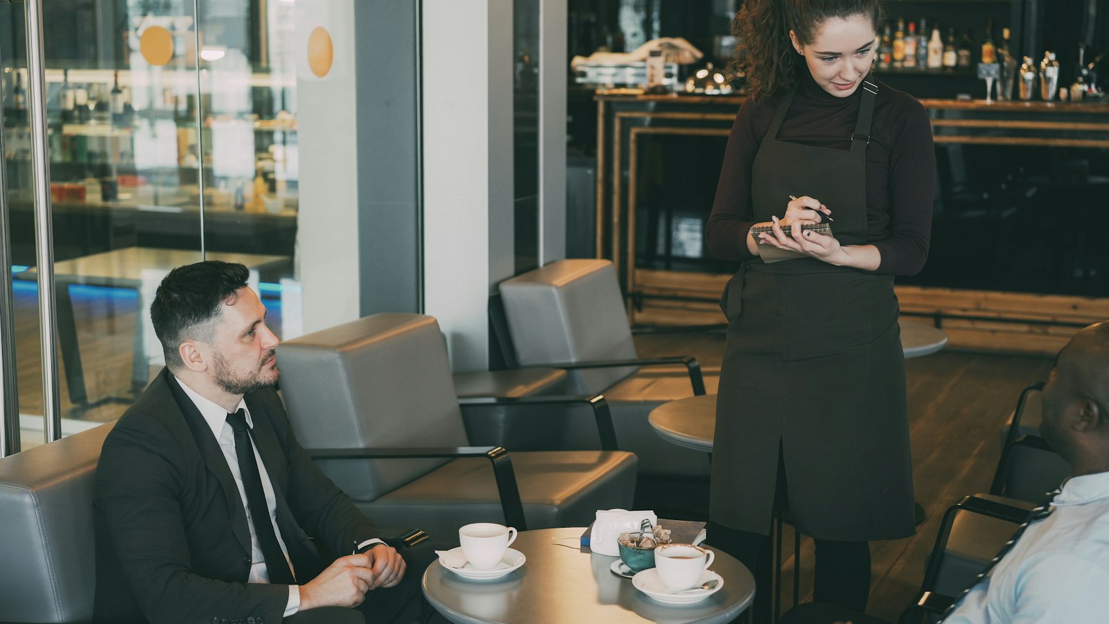 Serveuse en tablier prenant une commande dans un café : la classification et la rémunération des salariés en HCR