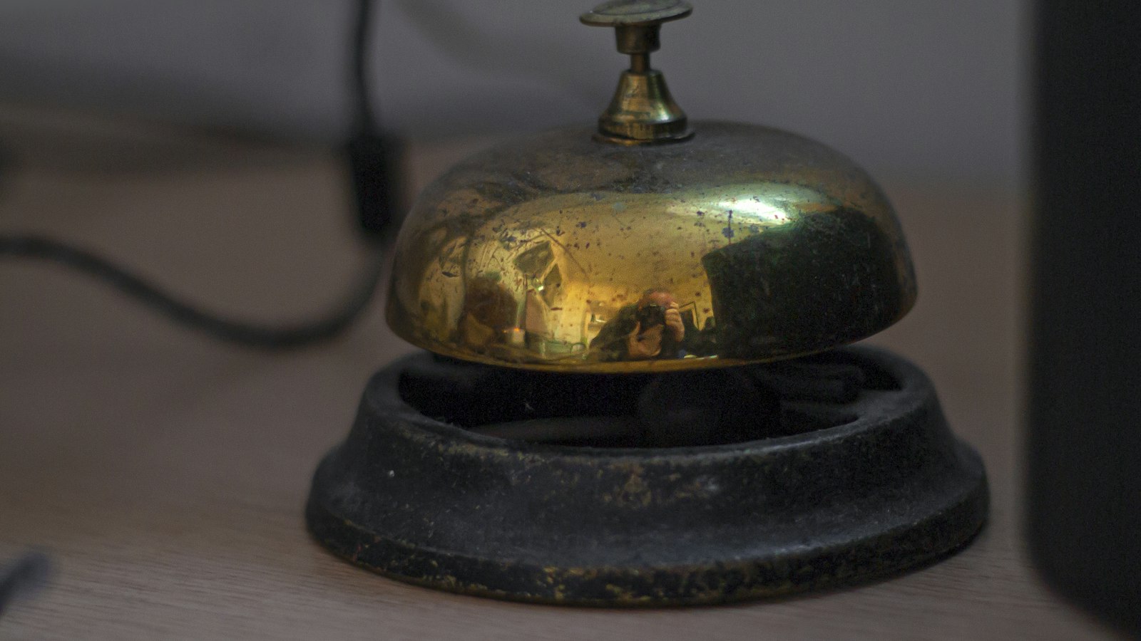 Sonnette de réception en laiton sur un comptoir en bois : ressources pratiques pour l'employeur des hôtels, cafés, restaurants