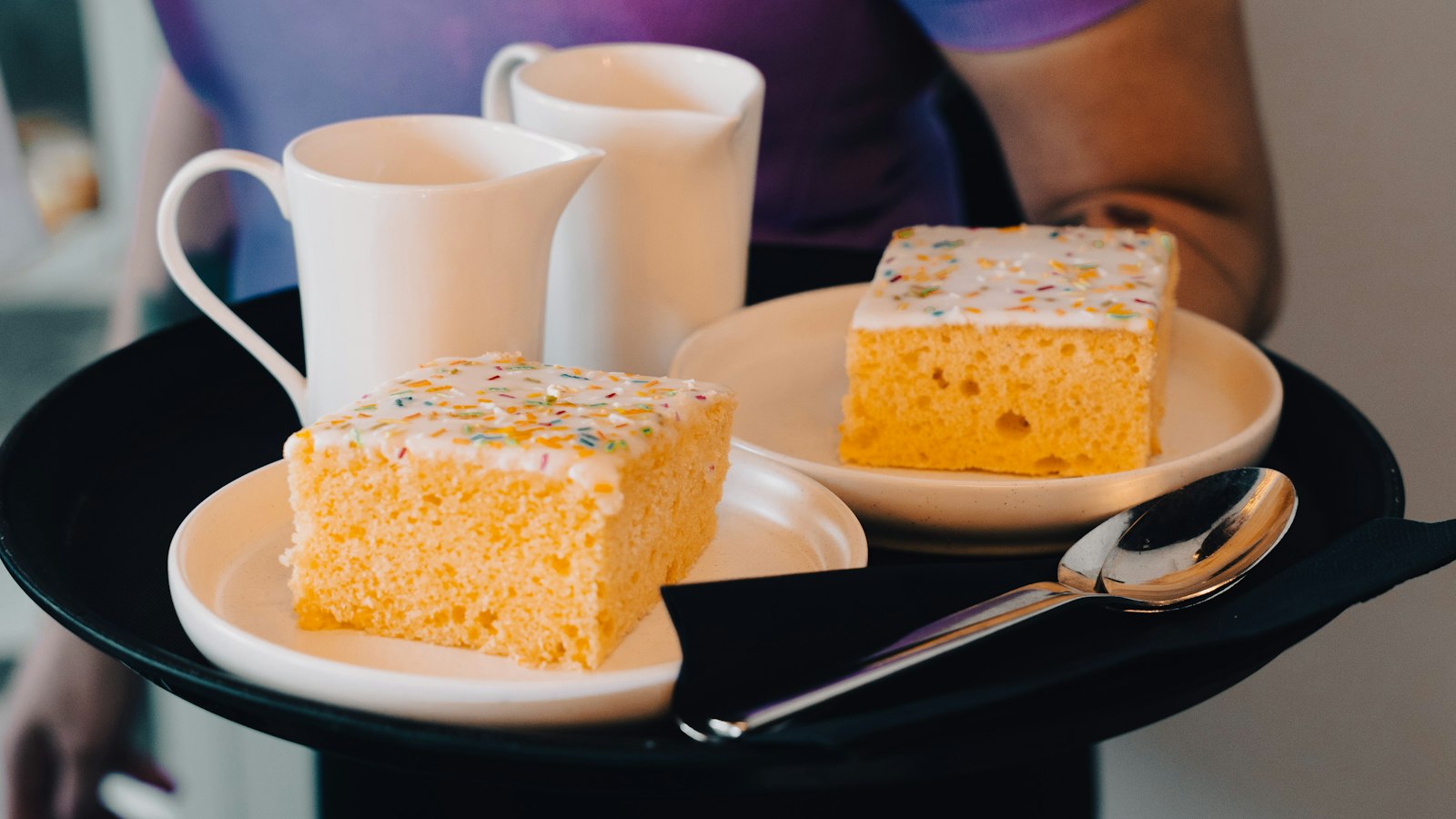 Serveuse portant un plateau de gâteaux et de cafés : les salaires minima conventionnels en HCR